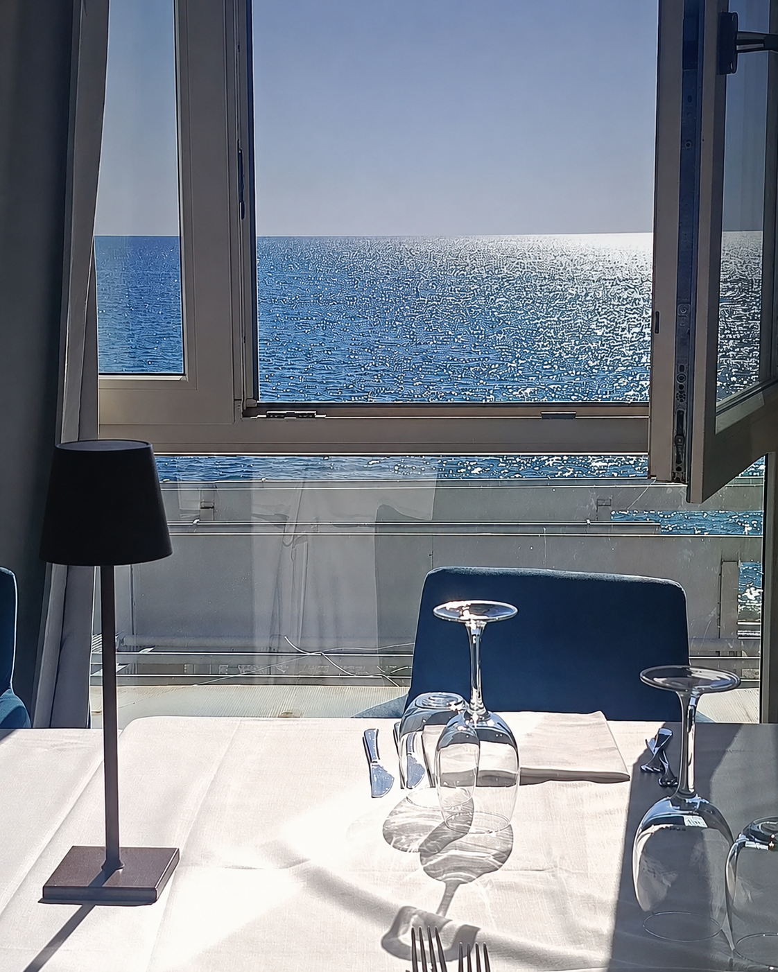 Tavolo apparecchiato con vista mare dalla finestra della sala