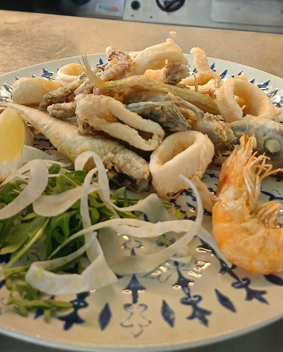 Fritto misto di calamari, gamberi e pesce fresco servito su piatto decorato