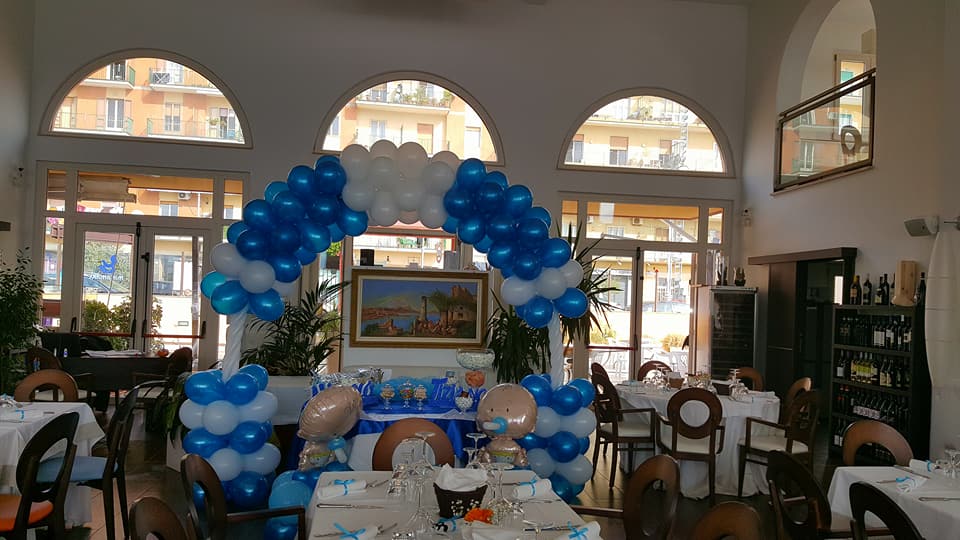 Sala interna allestita con arco di palloncini blu e bianchi per battesimo